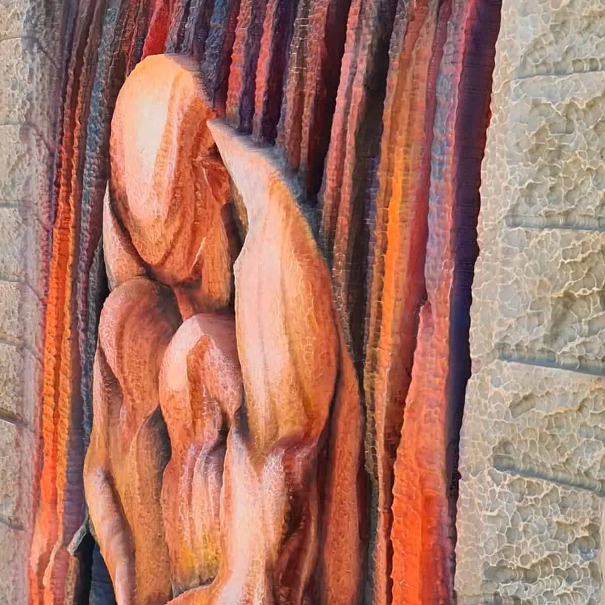 Refugio de Silencio - Esta escultura mural, que parece susurrar calma, captura la figura humana, abstracta pero cercana, fundidas en un abrazo propio que transmite calidez y consuelo. Está protegida por un fondo de franjas verticales llenas de color; casi puedes sentir el movimiento suave y la energía silenciosa que emanan. Los paneles laterales recuerdan a viejas piedras, sólidas e inamovibles: como si todo ese refugio nos invitara a respirar hondo y dejar fuera el ruido del mundo. Es un lugar donde hasta el más mínimo silencio pesa bonito-y es que ahí parece posible reencontrarse con un poco de paz interior.