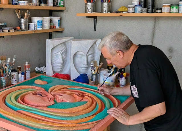 Antonio Gea pinta, con dedicación, un lienzo vibrante donde se entrelazan dos rostros abstractos. En su taller -repleto de pinceles gastados, tubos de pintura abiertos y modelos de rostros tallados- todo parece contar historias; la pared es de cemento frío y el desorden artístico revela concentración e impulso. Además, hay algo en su gesto que transmite pasión por el arte: mezcla colores como quien busca respuestas o tal vez redención.